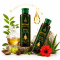 Two bottles of Attari Herbal Oil Special 11+12 are displayed on a white background with decorative props including a glass bottle of oil, a red hibiscus flower, green and brown nuts, leaves, and a rock.